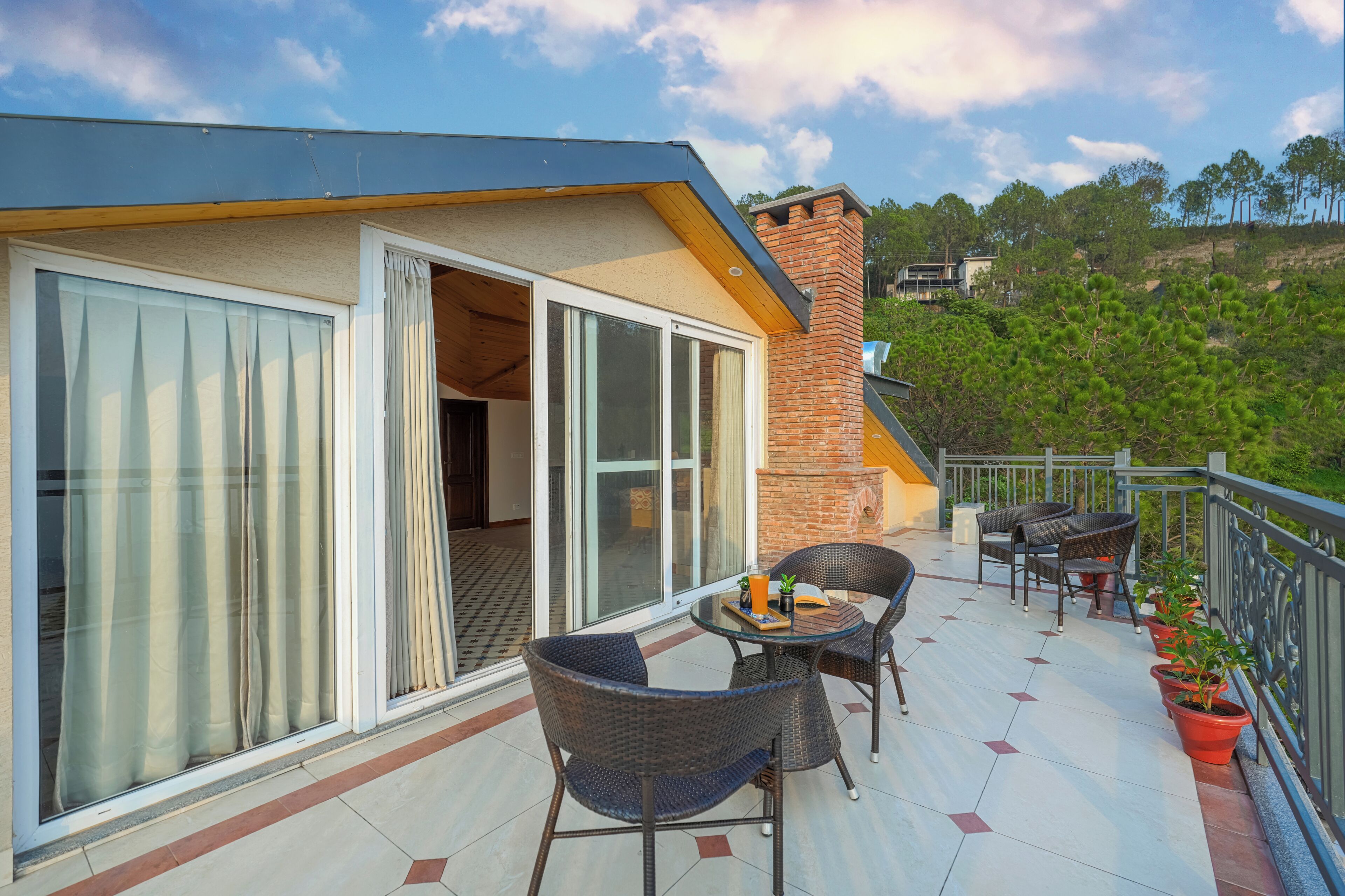 A balcony with outdoor furniture, a brick wall, and a view of greenery.