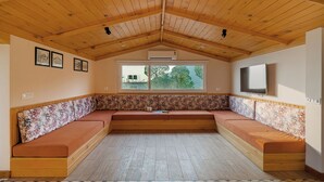 A room with a wooden ceiling, a large window, a bench, and a flat-screen TV. - Konifer Villas By ELIVAAS (Kasauli)