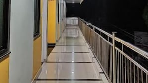 A long, narrow corridor with tiled floors and a metal railing on one side. - Hotel Gananjaya Gokarna (Gokarna)