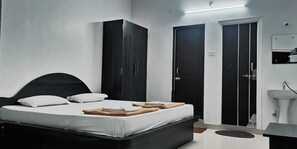 A bedroom with a bed, wardrobe, and a bathroom with a sink. - Hotel Gananjaya Gokarna (Gokarna)