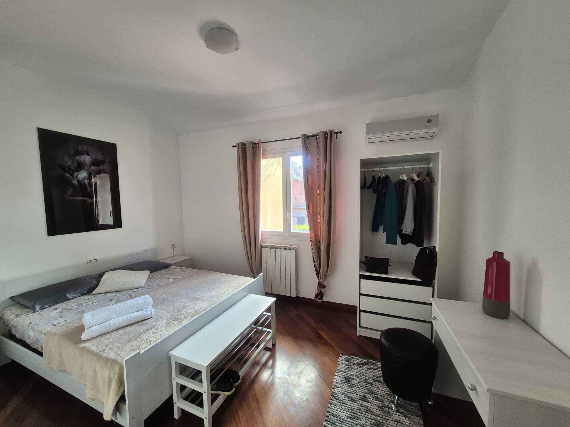 Une chambre à coucher comprenant un lit, un banc, un bureau, une armoire et un radiateur.