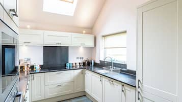 A modern kitchen with white cabinets, a black countertop, and a skylight.