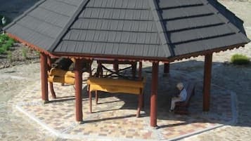 A gazebo with a tiled floor and benches, surrounded by a stone patio.