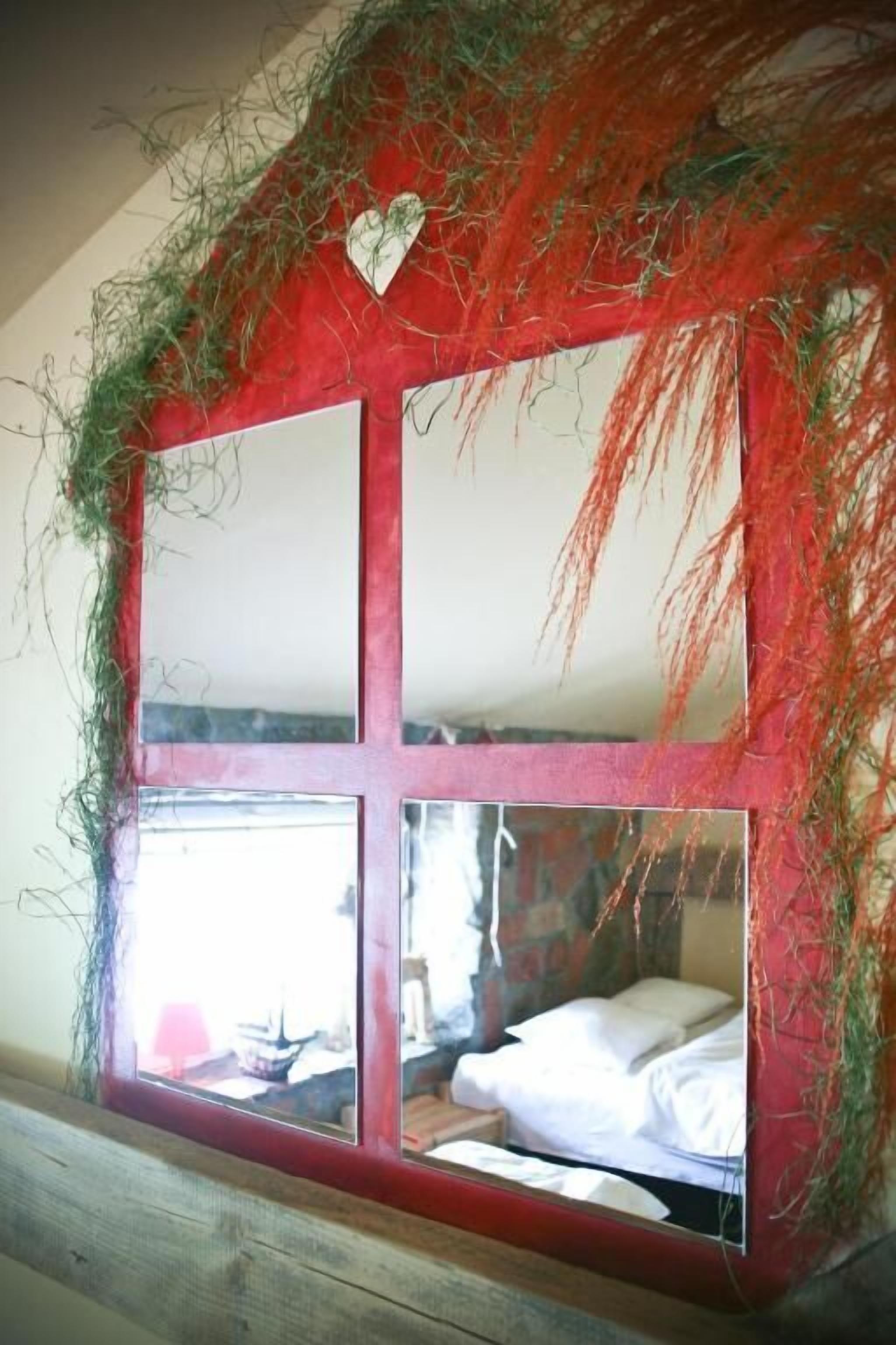 Una habitación con un espejo grande que refleja una cama y una ventana.