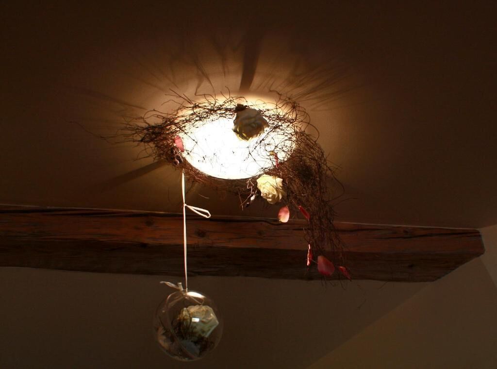 A ceiling with a rustic wooden beam, a hanging light fixture, and a clear glass ornament.