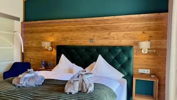 Een kamer met houten lambrisering, een bed, kussens, een groen hoofdeinde en wandlampen.