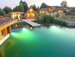 A wooden cabin-style hotel with a swimming pool, a dock, and a waterfall feature.