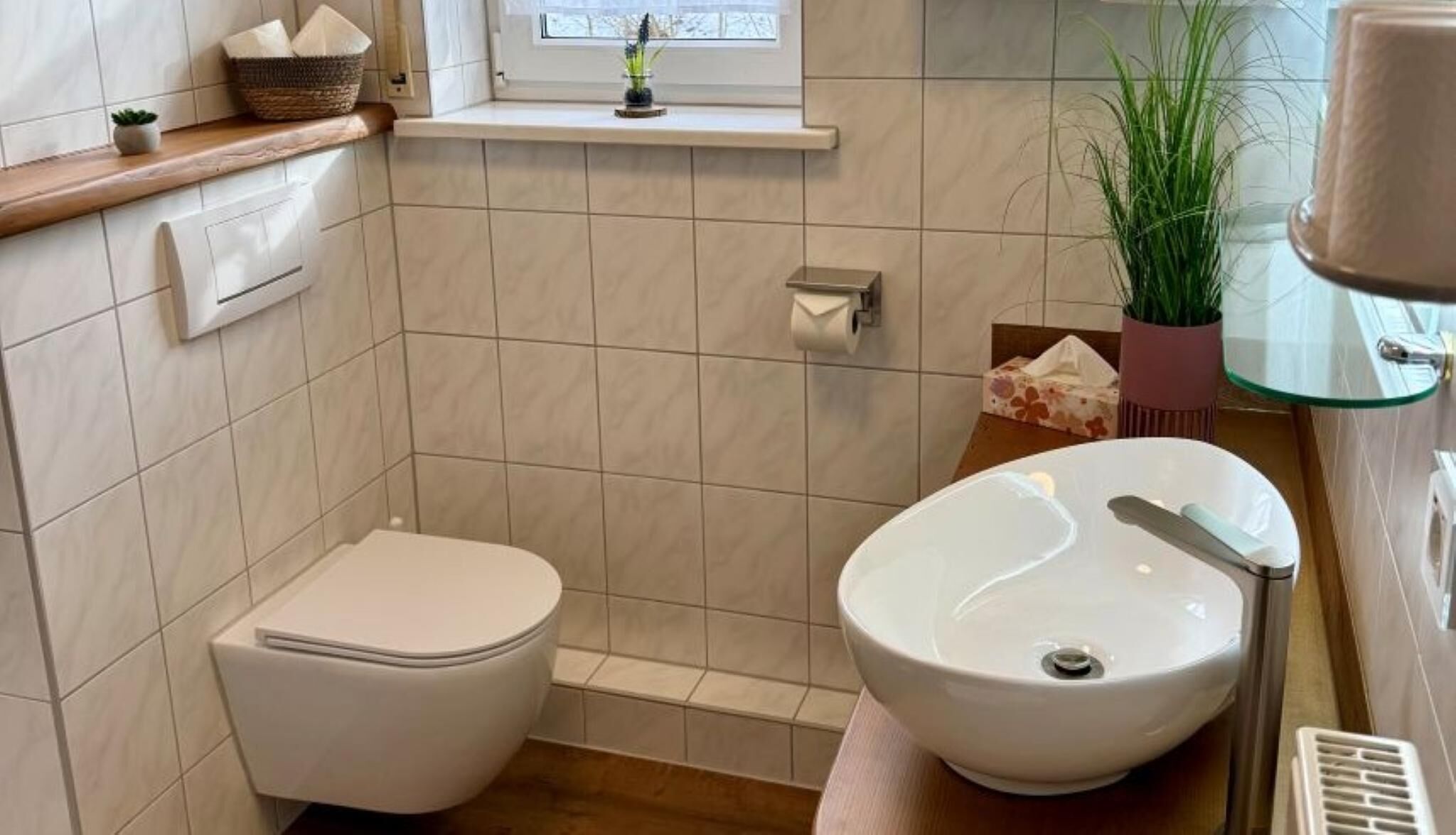 Ett badrum med toalett, handfat, dusch och ett fönster.