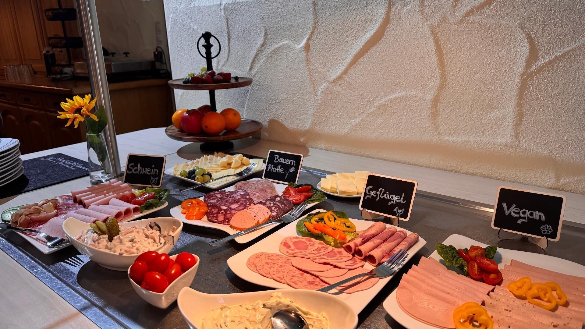 Un bufé con diversas opciones de comida, incluyendo carnes, quesos y verduras.