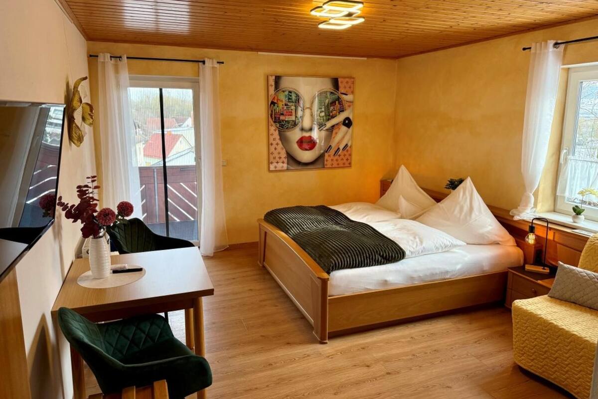 Een slaapkamer met een bed, een bureau, een stoel, een spiegel en een muur met gezichtsschildering.