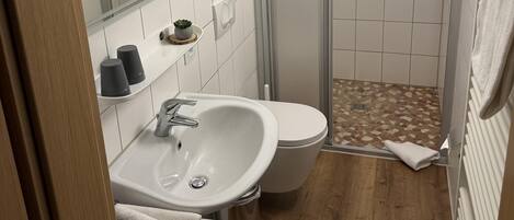A bathroom with a sink, toilet, and shower area.