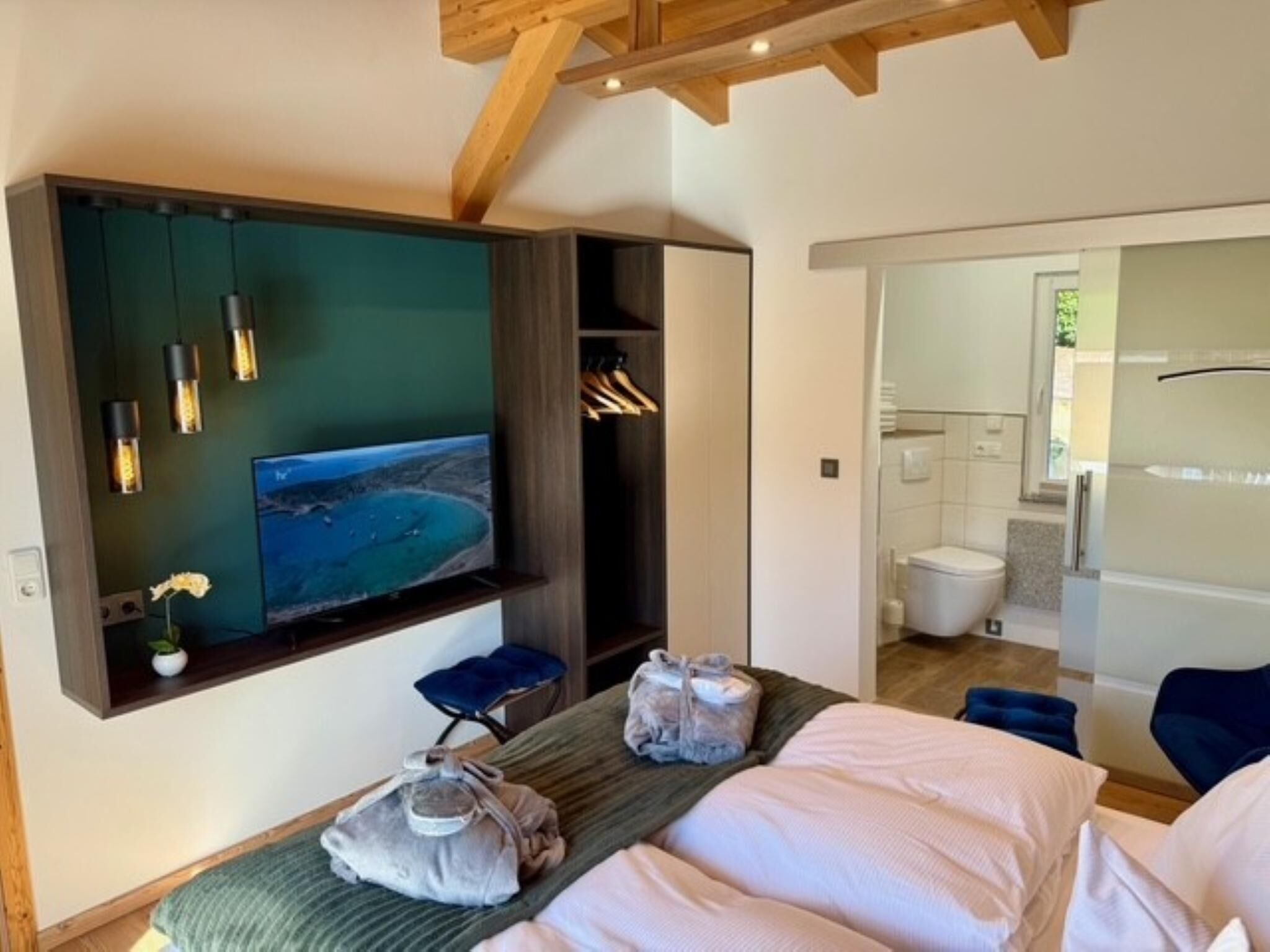 Ett rum med en säng, en TV, ett badrum och utsikt över havet.