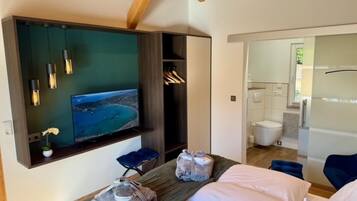 Ett rum med en säng, en TV, ett badrum och utsikt över havet.
