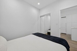 A bedroom with a bed, a wardrobe, and a door leading to a bathroom. - 2BR | Downtown | AC | Mins to Saddledome (Calgary)