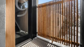 A modern building entrance with a glass door, a wooden fence, and a clear view of the outside. - Ember House | Lux 2 Bed | Min to DT (Calgary)