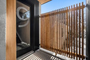 A modern building entrance with a glass door, a wooden fence, and a clear view of the outside. - Ember House | Lux 2 Bed | Min to DT (Calgary)