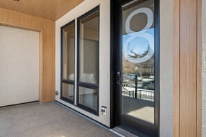 A modern building entrance with a glass door and a view of a snowy street. - The Platinum Stay | Luxury 2 Bed | Min to DT (Calgary)