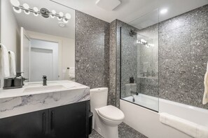 Ein modernes Badezimmer mit Marmorwaschtisch, Toilette, einer Duschkabine und einer Badewanne.