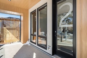 Ein modernes Gebäude mit großen Glasüren, einem Holzzaun und einem Betonboden.