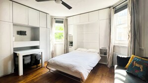 Una camera da letto con un letto, una scrivania e una sedia, con pavimento in legno e una finestra.