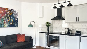 Una cucina moderna con mobili bianchi, una cappa aspirante nera e un forno integrato.