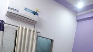 A bedroom with a bed, a wardrobe, a mirror, and an air conditioning unit. - Hotel Deep (Shri Madhopur)