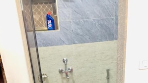 A bathroom with a shower, toilet, and a yellow bucket on the floor. - Hotel Deep (Shri Madhopur)