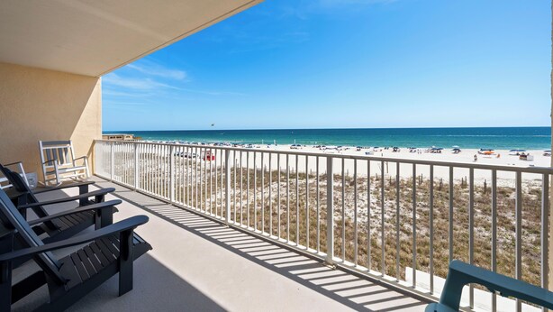 Un balcon donnant sur la plage, avec une balustrade et deux chaises longues.