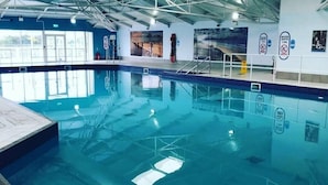 An indoor swimming pool with clear water, tiled floors, and safety signs on the walls. - Greenacres Holiday Park - Holiday Accommodation 15761 (Porthmadog)