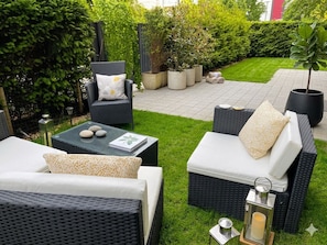 An outdoor seating area with wicker furniture, a small table with stones, and potted plants.
