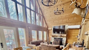A log cabin interior with a dining area, a fireplace, and a mounted deer head. - A Custom-Built Swiss-Style Luxury Mountain Retreat - Upper Level 3 BR Unit (Mount Jackson)