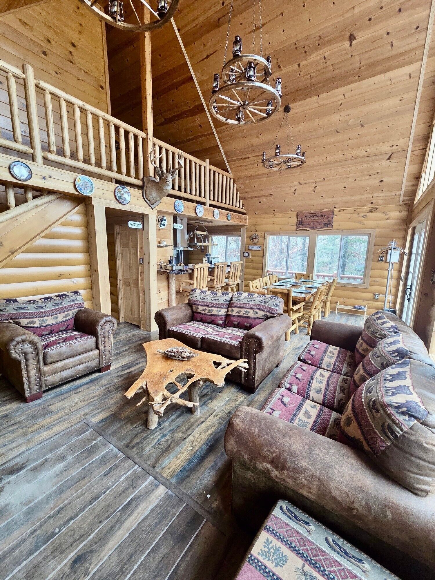 Ein rustikaler Innenraum einer Blockhütte mit Essbereich, zwei Sofas, einem Holztisch und einer Küchenzeile.