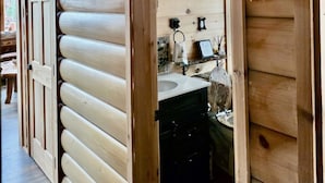 A wooden cabin interior with a visible bath area, a sink, and a hanging bath sign. - A Custom-Built Swiss-Style Luxury Mountain Retreat - Upper Level 3 BR Unit (Mount Jackson)