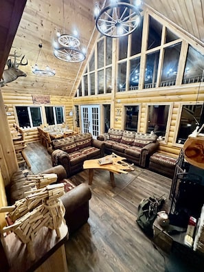Ein Holzblockhaus-Interieur mit einem großzügigen Sitzbereich, Holzwänden und mehreren Fenstern.