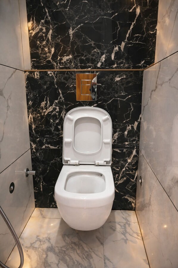 Une salle de bain moderne avec un mur en marbre, des toilettes blanches et un panneau en bois au-dessus des toilettes.