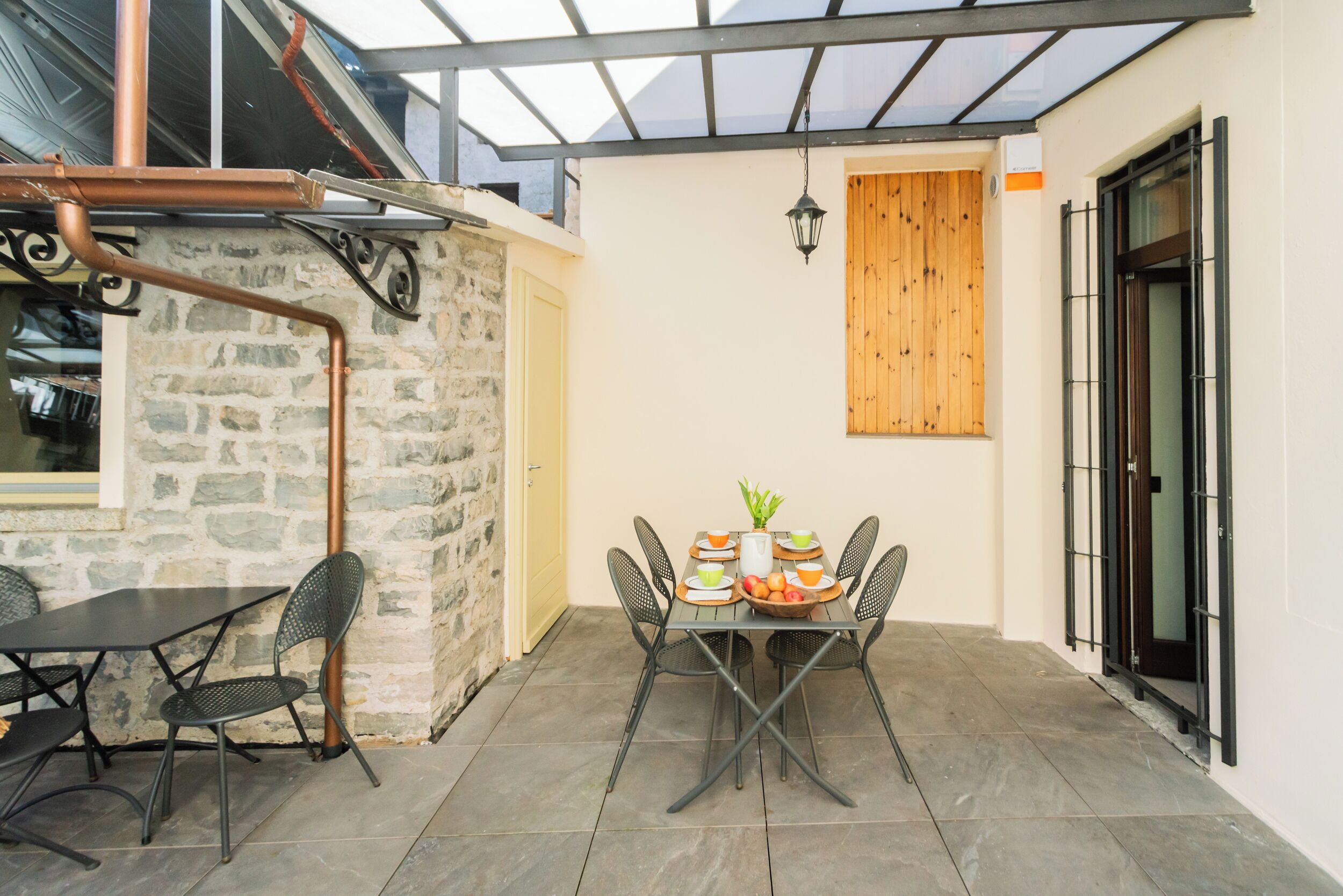 A patio with a table and chairs, a stone wall, and a wooden door.