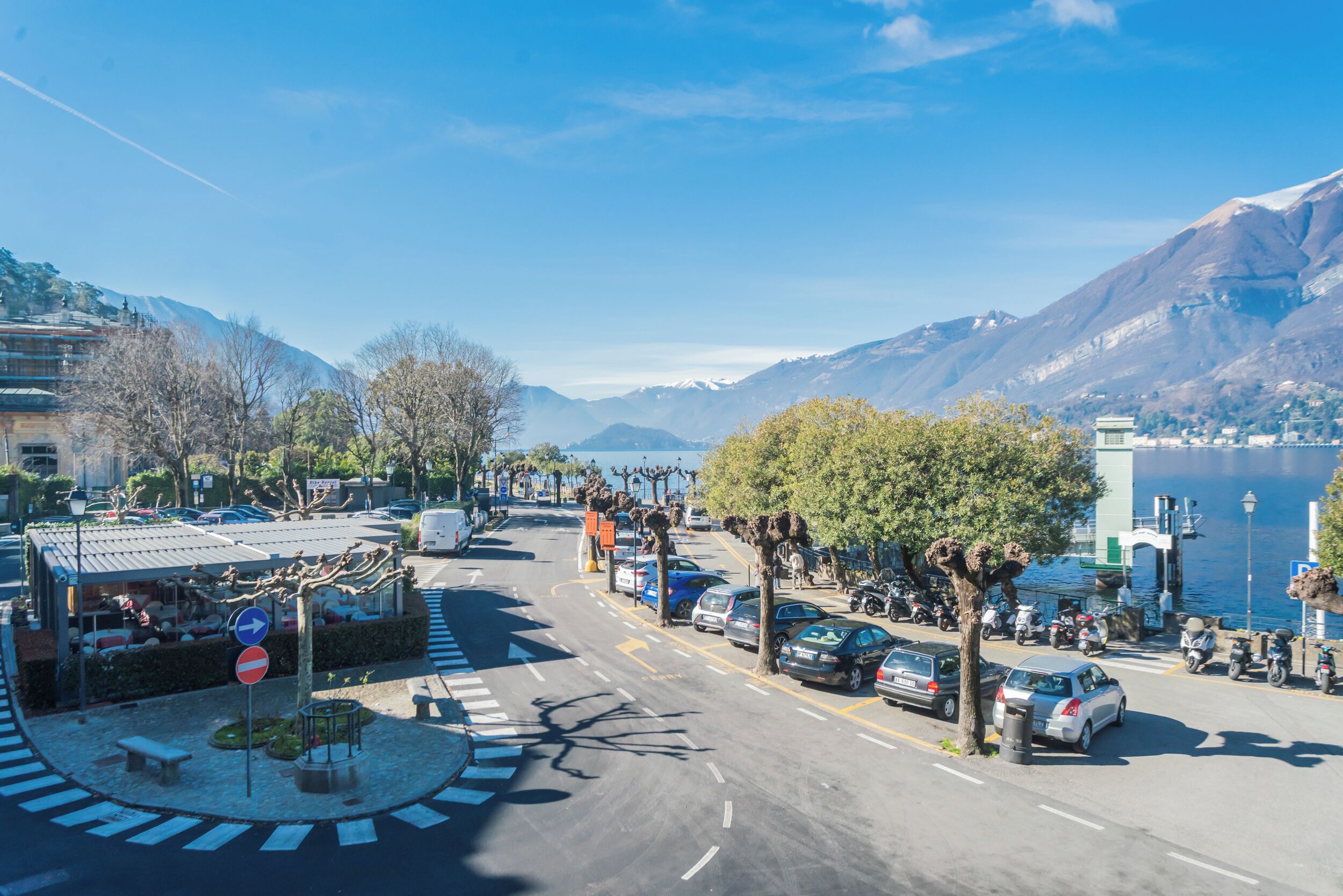 A street with cars, trees, and a mountain in the background.