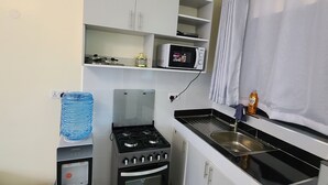 Uma cozinha compacta com fogão a gás, forno, micro-ondas e dispensa para água.