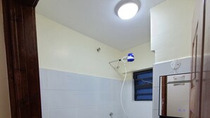 Uma casa de banho com sanita, lavatório, chuveiro e espelho.