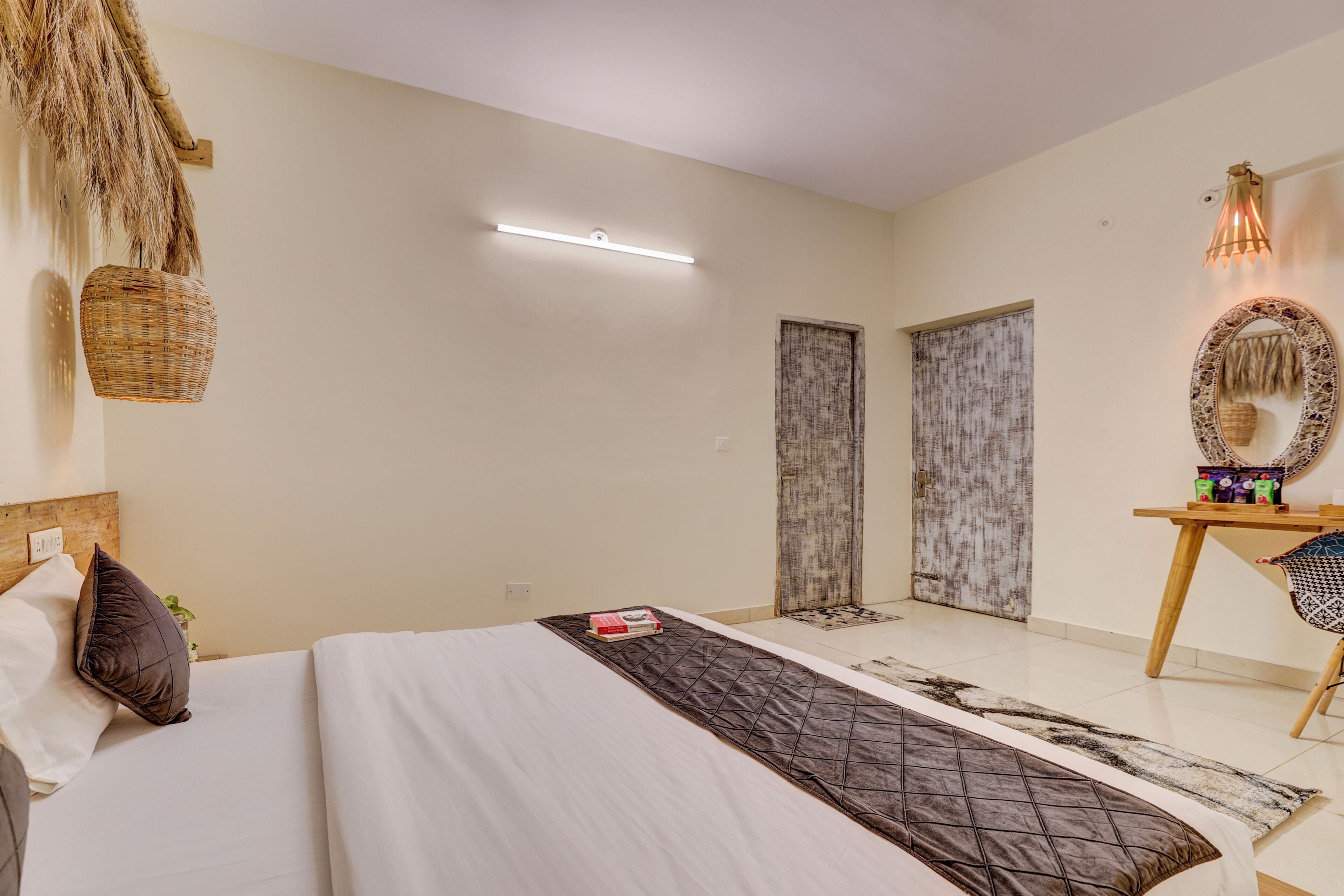 Quarto com cama, mesa de cabeceira, luminária e espelho na parede.