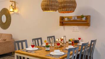 A dining area with a wooden table, chairs, and hanging wicker lamps.