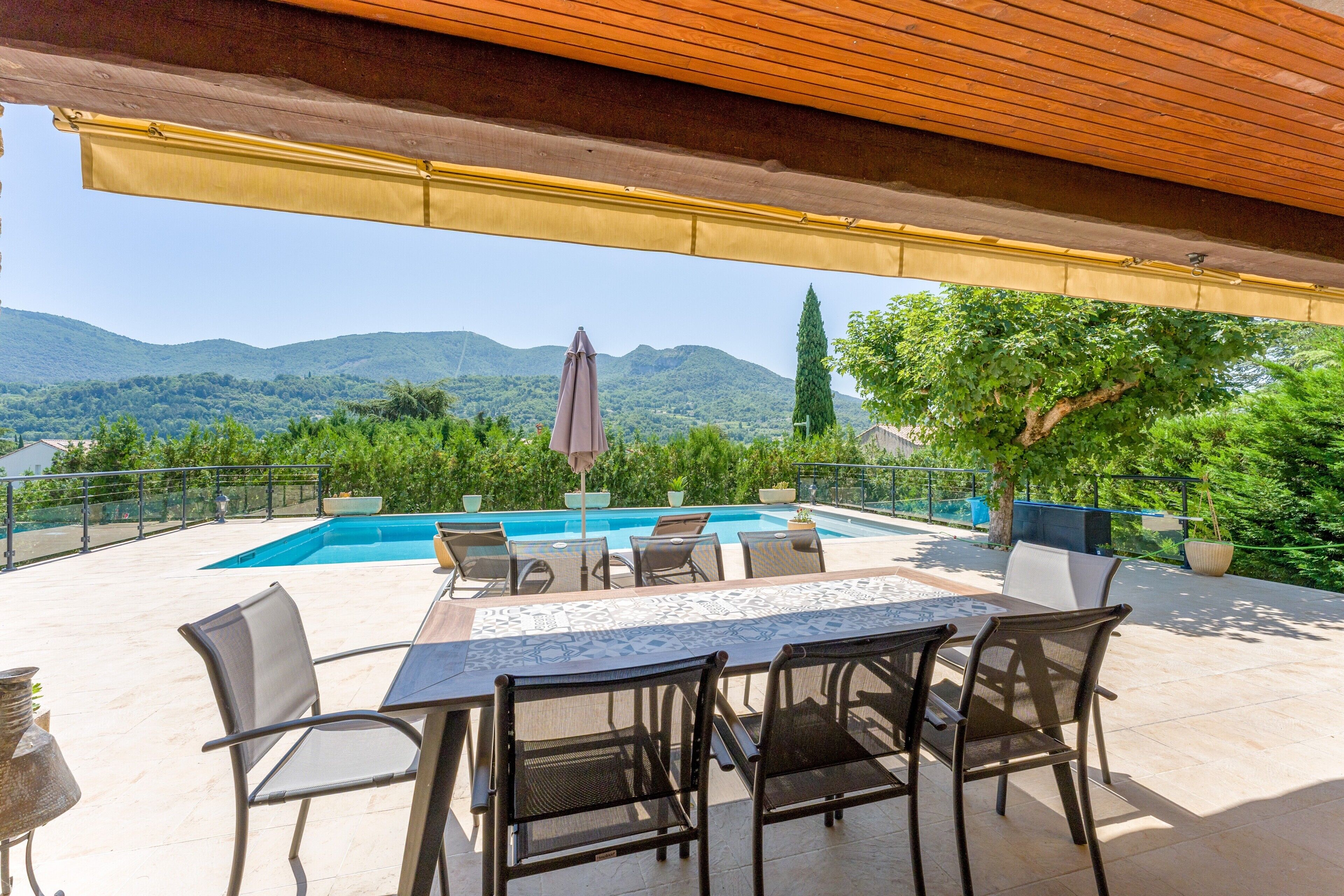 An outdoor patio with a pool, seating, and a view of mountains.