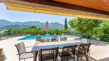An outdoor patio with a pool, seating, and a view of mountains.