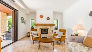 Un salon avec une cheminée, deux fauteuils, un canapé et une table basse.