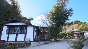 A traditional Japanese building with a stone wall, a wooden fence, and a clear sky. - Bungee Inn (Minamiizu)