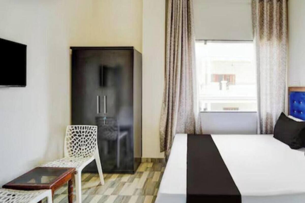 A hotel room with a bed, a wardrobe, a chair, and a small table.