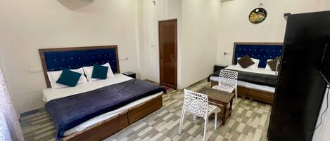 Una habitación de hotel con cama, escritorio, dos sillas, televisor y aire acondicionado.