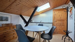 A kitchen with a skylight, wooden cabinets, a dining table with chairs, and a small stool. - Vacation apartment FR1 - "Seewohnung" - Holiday apartment "Seewohnung" with (Graal-Müritz)