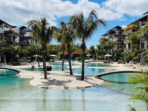 Un resort con diverse piscine, palme e edifici moderni.