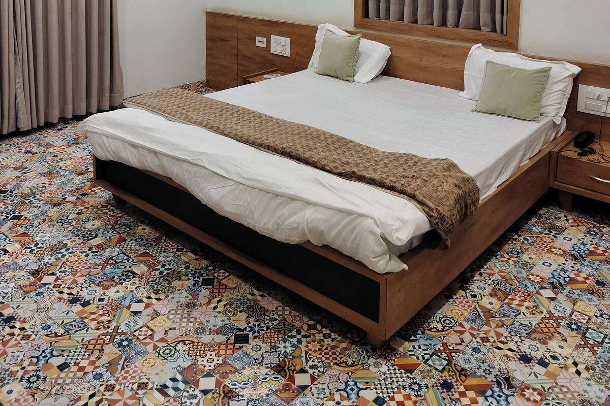 A neatly made bed with a wooden headboard, a ceiling fan, and a patterned floor.